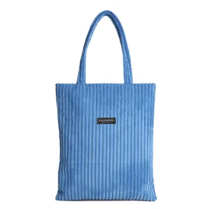 Borsa tote in velluto a coste blu con strisce verticali ed etichetta moda su sfondo bianco