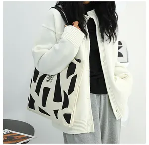 Detail of a large canvas tote bag with black and white geometric patterns on a model