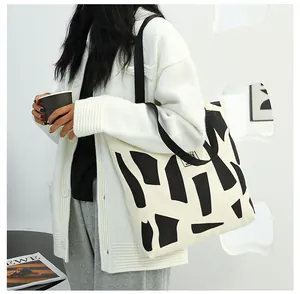 Minimalist canvas tote bag with black abstract geometric patterns shown on shoulder