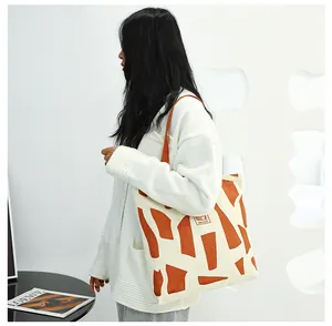 Canvas tote bag with orange geometric pattern and shoulder strap for daily commuting