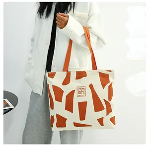 Close-up of cream canvas tote bag with orange geometric patterns and Good Student print