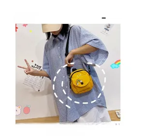 Detail of a yellow canvas crossbody bag with a cute rainbow patch and adjustable strap