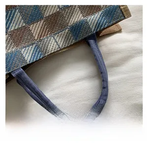 Detail of blue rope handle and coarse textured plaid canvas on the tote bag