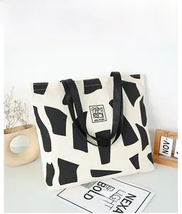 Detail of minimalist cream canvas tote bag with black geometric art and cartoon patch