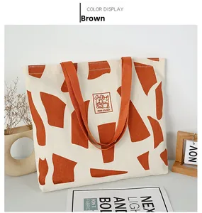Detail of canvas tote bag with brown geometric print and orange woven straps for school