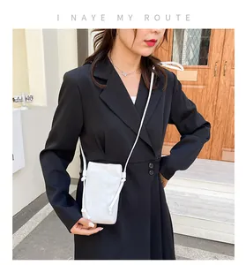 Detail van een witte mini crossbody telefoontas met koordbandjes op een zwarte blazer