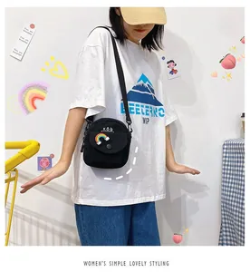 Detail of cute black canvas crossbody bag featuring rainbow cloud embroidery and magnetic buckle