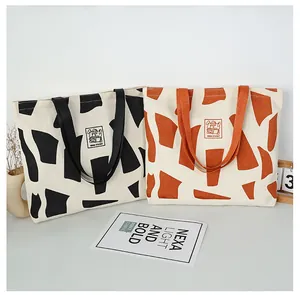 Close-up of geometric canvas tote bags with Good Student bunny patch and thick fabric texture
