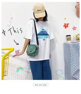 Detail of avocado green canvas crossbody bag featuring a rainbow patch and front pocket