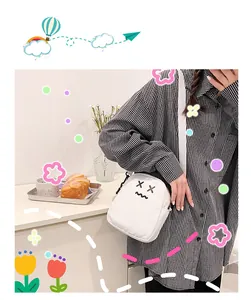 Close-up of white canvas crossbody bag with cartoon face embroidery on a girl