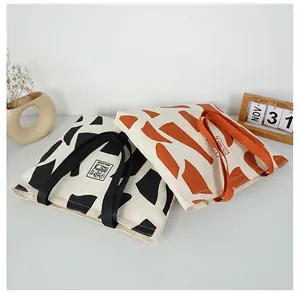Detailed top view of two large canvas tote bags with artistic geometric patterns and thick handles