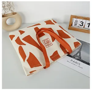 Detail of canvas tote bag showing large orange geometric pattern and matching strap handles