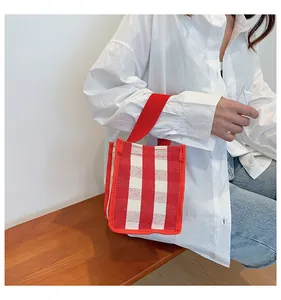 Détail d'un sac à main en toile à carreaux vichy rouge et blanc porté par un mannequin