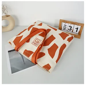 Detailed top view of large canvas tote bag with giraffe print and orange handle on desk