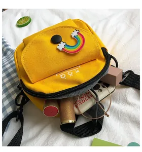 Interior view of yellow canvas crossbody bag showing phone, glasses and lipstick storage