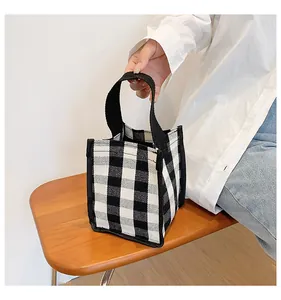 Gros plan du sac à main minimaliste en toile à carreaux noir et blanc sur un tabouret