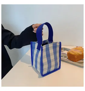 Gros plan sur un sac en toile à carreaux bleu et blanc avec anses tissées bleu marine
