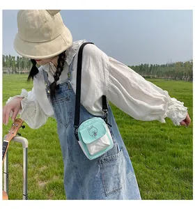 Outdoor shot of a mint green canvas crossbody bag with a cute cartoon bear print