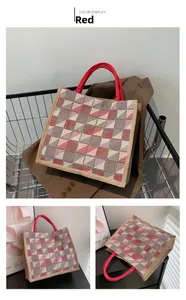 Macro detail of red plaid canvas tote bag showing weave texture and sturdy red handles