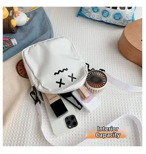 Internal capacity of white cartoon crossbody bag showing phone and cosmetics