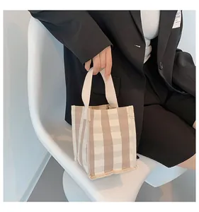 Détail du mini sac cabas en toile à carreaux avec poignées tissées et style épuré