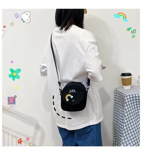 Close-up of a small black canvas crossbody bag with rainbow patch and KǑQ logo