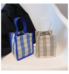 Détail de mini sacs à main en toile rayée bleue et beige sur une chaise pour maquillage