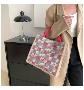 Detail of red checkered canvas tote bag with woven handles shown in a lifestyle setting