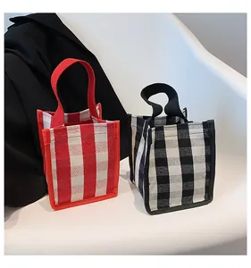 Détail de mini sacs cabas en toile à carreaux rouges et noirs sur chaise blanche