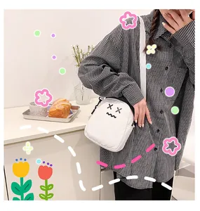 Detail of cute white canvas crossbody bag with cartoon embroidery and wide strap