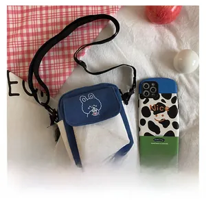 Detail shot of canvas crossbody bag with rabbit embroidery and cow print phone case