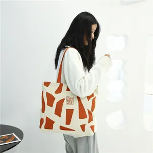 Large canvas tote bag with orange geometric print and Good Student patch for daily commute