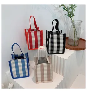 Gros plan de mini sacs cabas en toile à carreaux rouges, bleus et noirs sur socle blanc