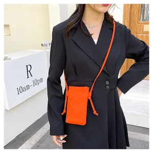 Detailopname van de mini oranje canvas crossbody telefoontas op een zwarte blazer