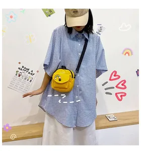 Detail of yellow canvas crossbody bag featuring rainbow patch and front snap pocket