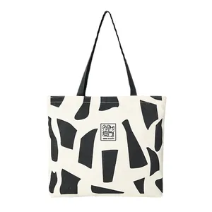 Minimalist cream canvas tote bag with black geometric patterns and cartoon rabbit print
