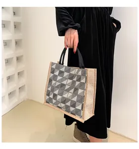 Detail of checkered canvas tote bag with woven handles shown in a lifestyle setting