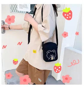 Primer plano de bolso bandolera de lona negra con lindo estampado de dibujos animados
