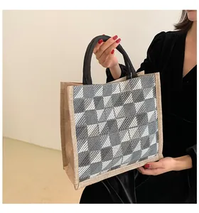 Detail of grey plaid canvas tote bag with black woven handles and textured fabric finish
