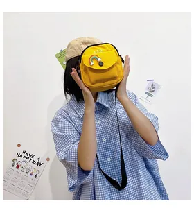 Detail of yellow canvas crossbody bag featuring rainbow cloud embroidery and kòq logo
