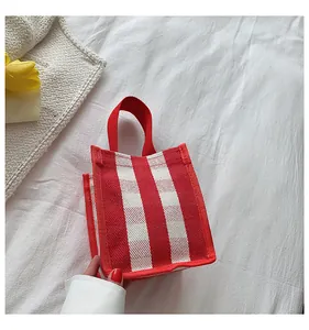 Détail d'un mini sac cabas en toile à rayures rouges et blanches avec poignées