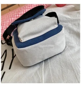 Detail of blue and beige canvas crossbody bag with adjustable strap and front flap pocket