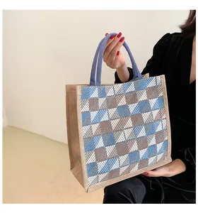 Detail of checkered canvas tote bag with reinforced light blue handles and textured fabric