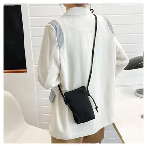 Minimalistische zwarte canvas telefoontasje gedragen door een model voor een casual look