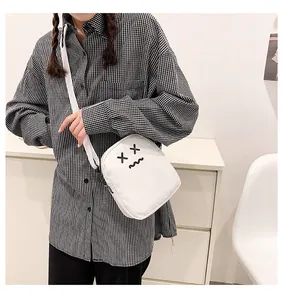Close-up of white canvas crossbody bag with cute cartoon embroidery and adjustable strap