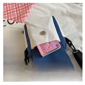 Detailed view of the magnetic buckle and front pocket of the blue canvas crossbody bag