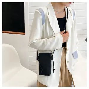 Minimalistische zwarte canvas mini-telefoontas gedragen met een witte blazer outfit