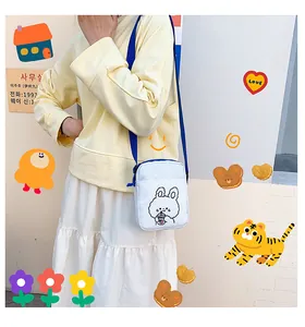 Detalle de bolso de lona blanco con estampado de conejo y correa azul ajustable