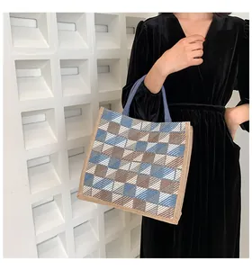 Close-up of woven canvas tote bag with blue and brown plaid pattern and reinforced edges