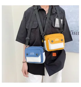 Detail of blue and yellow canvas crossbody bags with adjustable straps and KoQ logo